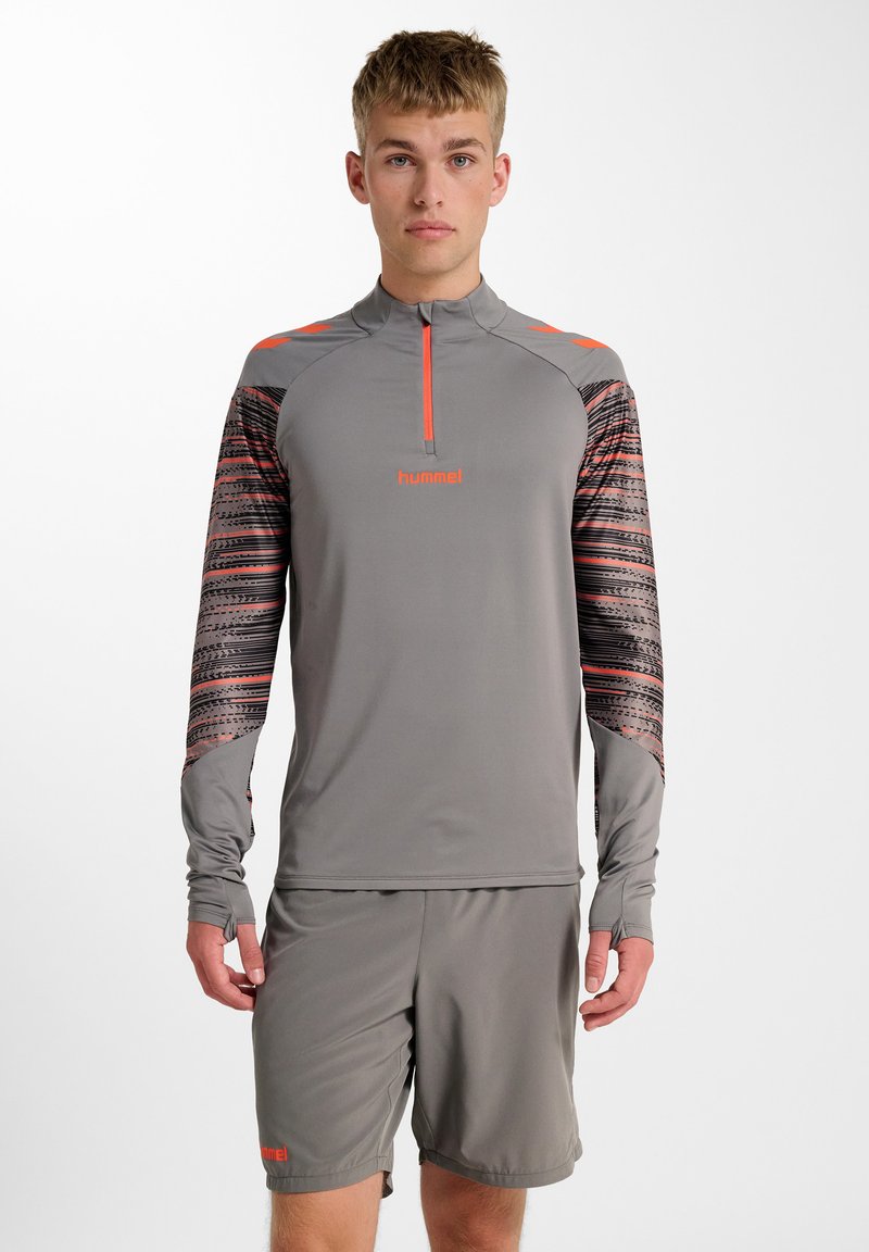 Graues Sportoberteil mit einem viertel Reißverschluss, langen Ärmeln und lebhaften orangen Akzenten; gemusterte Ärmel mit einem strukturierten Design.