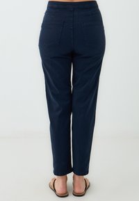 Pantaloni blu navy con design a gamba dritta, caratterizzati da una vita piatta e due tasche posteriori. Il tessuto appare morbido con una texture liscia.