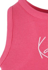 Ribbete rosa stofftanktop med rund halslinning og hvit broderi detalj foran, som viser en jevn tekstur og tett passform.