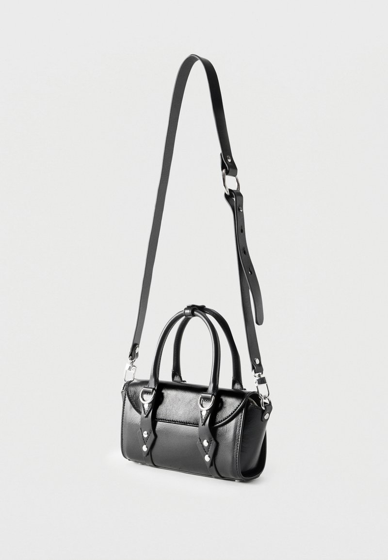 Bolso bandolera de cuero negro con dos asas cortas, herrajes plateados y una correa larga ajustable colgado sobre un fondo claro.