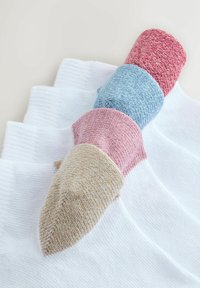 Pamut zoknik három színben: piros, kék és bézs, mindegyik texturált kötettel és kontrasztos színű szegéllyel, fehér háttéren elrendezve.