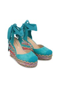 Les sandales compensées turquoise présentent un dessus en daim, un talon en tricot et une semelle en jute tressé multicolore. Des liens à la cheville complètent le design.