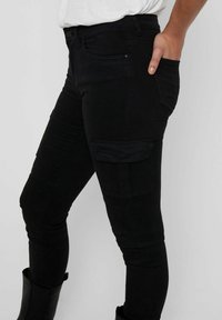 Pantalones cargo negros con un corte ajustado, bolsillo lateral y una costura texturizada sutil. Fabricados con un tejido suave y elástico para mayor comodidad.