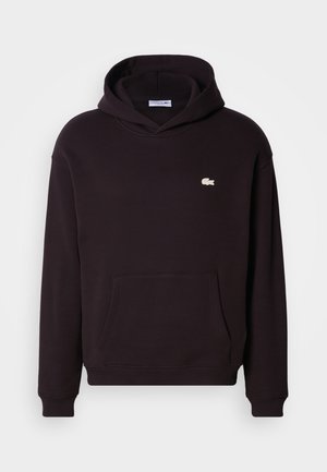 Svart hoodie med känguruficka, ribbade muddar och en liten vit logotyp på bröstet. Tillverkad av mjukt, texturerat tyg.