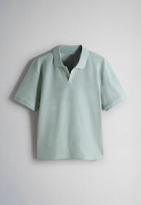 Világoszöld, rövid ujjú, bordázott kötött galléros póló rövid V-nyakkivágással, egyszerű világos háttér előtt bemutatva.