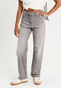 Grå højtaljede jeans med lige ben. Lavet af denim, med klassisk fem-lomme stil og subtil falming. Sammen med hvide sneakers.