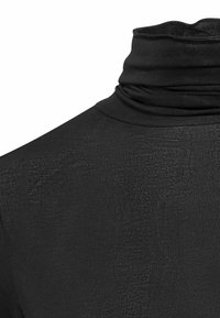 Zwarte coltrui met een zachte, geribbelde textuur en een getailleerd ontwerp. Het materiaal lijkt rekbaar en glad, geschikt voor lagen.