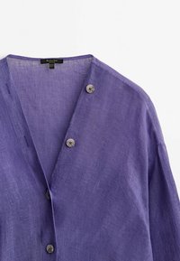 Chemise en lin violet à boutons avec un col en V, dotée de deux boutons à l'avant et d'un tissu texturé. Design simple et ample.