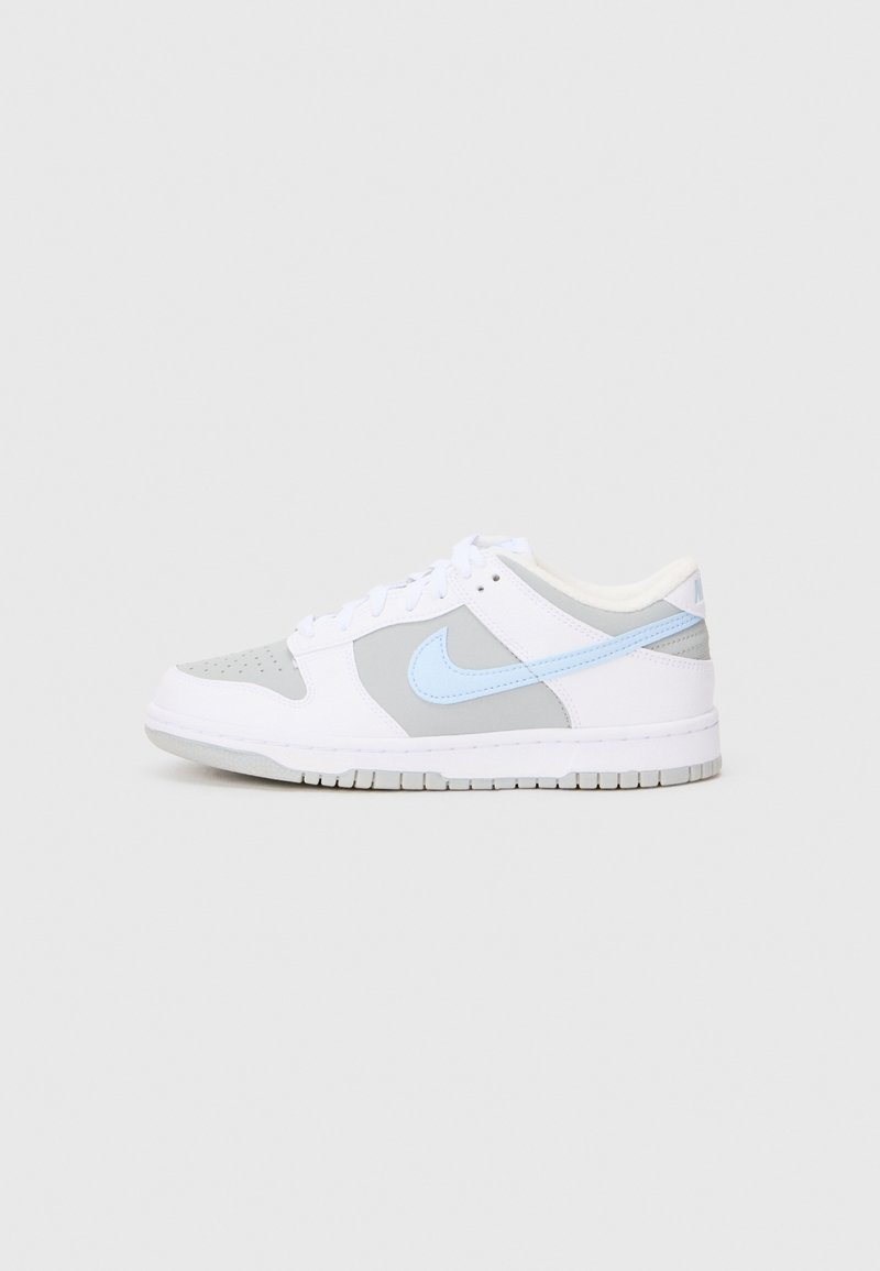 Bílé a šedé nízké tenisky se světle modrým Nike swoosh, bílými tkaničkami a perforovanou špičkou na jednobarevném pozadí.