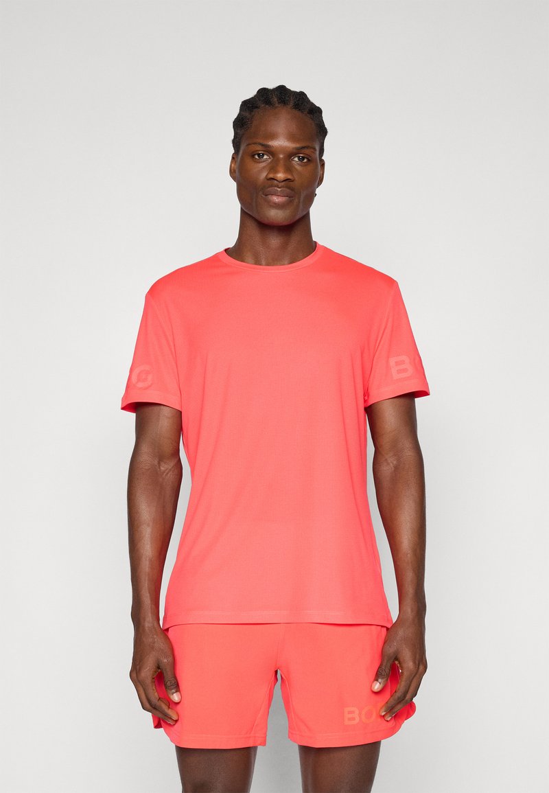 Men's athletic outfit featuring a short-sleeve, bright coral t-shirt and matching shorts, both made from lightweight, textured fabric.