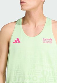 Mint zelena majica bez rukava s suptilnim grafičkim uzorkom, koja sadrži ružičasti Adidas logo i tekst "BMW BERLIN MARATHON". Lagani materijal.