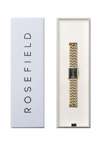 Goudkleurig horloge met een rechthoekige zwarte wijzerplaat en een kettinglink-armband, gepresenteerd in een wit en grijs doos met reliëf branding.