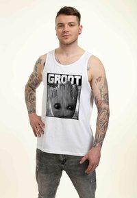 Camiseta sin mangas de algodón blanca con un estampado gráfico de Groot de "Guardians of the Galaxy Vol. 2" con texto negro y bordes.