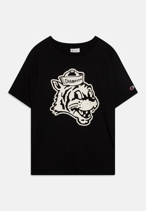 T-shirt en coton noir présentant un grand graphique blanc d'un tigre en cartoon portant une casquette étiquetée "CHAMPION". Manches courtes et encolure ronde.