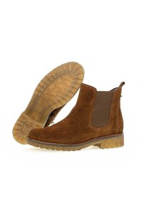 Stivaletti in suede marrone con pannelli elastici laterali, suola in gomma texturizzata e tacco basso. Presentano decorazioni in cucitura lungo il bordo.