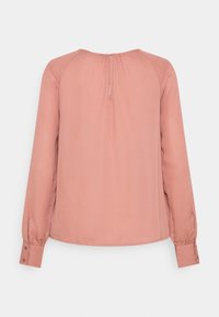 Blusa a maniche lunghe in morbido tessuto rosa, con scollo rotondo, chiusura posteriore con bottoni e dettagli arricciati sulle spalle e sui polsini.