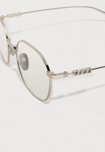 Óculos de sol com armação de metal prateado, lentes quadradas oversize e "Gucci" gravado nas hastes. Design minimalista com linhas elegantes.