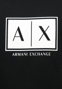 Λευκό ορθογώνιο λογότυπο Armani Exchange με τα γράμματα «A | X» πάνω από το όνομα της μάρκας σε μαύρο υφασμάτινο φόντο.