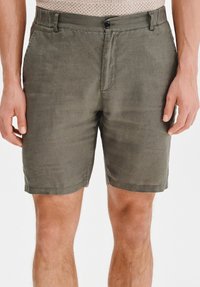 Oliwkowe lniane szorty o prostym kroju, z zapięciem na guzik z przodu i bocznymi kieszeniami, gładką fakturą i czystym wykończeniem dołu.