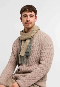 Stickad tröja i ljusrosa med texturerat mönster, kombinerad med en mönstrad salviagrön scarf med fransar och en "bugatti"-etikett.