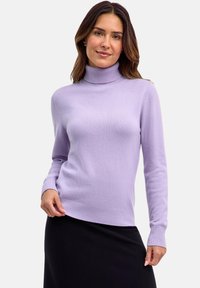 Maglione a collo alto di colore lilla chiaro, realizzato in un morbido tessuto testurizzato. Presenta polsini e orlo a coste, indossato sopra una gonna nera.