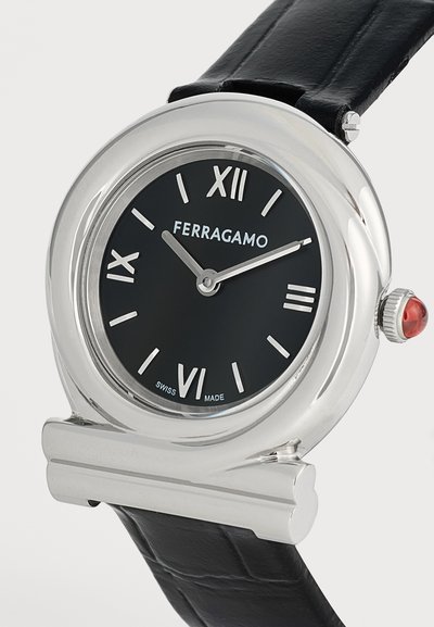 Ρολόι χειρός Ferragamo με μαύρο δερμάτινο λουράκι, ασημένια στρογγυλή κάσα, μαύρο καντράν, ρωμαϊκούς αριθμούς και ασημένιες δείκτες ωρών και λεπτών.