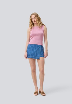 Top senza maniche rosa a coste, gonna avvolgente in denim blu con strisce bianche, mules con tacco a blocco marroni. Design semplice, vestibilità casual.