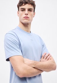 Világoskék pamut rövid ujjú póló kerek nyakkivágással. Minimalista dizájn minták vagy szöveg nélkül, sima textúrájú.