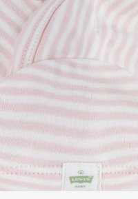 Tkanina s ružičastim i bijelim prugama, mekane teksture, s oznakom "Levi's Baby" na dnu. Okrugli izrez, ležeran dizajn.