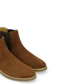 Bottes à cheville en daim marron avec des panneaux latéraux élastiques et un bout arrondi. Présente une semelle texturée contrastante avec des détails cousus.