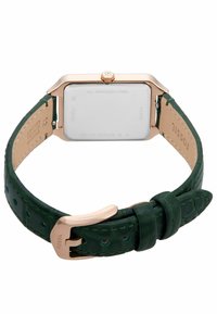 Montre avec un bracelet en cuir vert et un boîtier en acier inoxydable rectangulaire. Présente un bracelet texturé et des accents dorés sur le boîtier et la boucle.