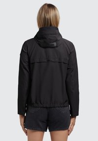 Black lightweight jacket with a drawstring hem and hood, featuring a logo patch on the back and a smooth, water-resistant fabric.