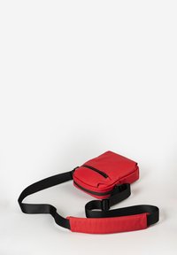 Borsa a tracolla rossa realizzata in materiale sintetico liscio, con chiusura superiore a zip, tracolla nera regolabile e forma rettangolare compatta.