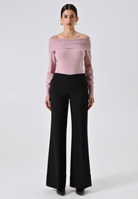 Maglione rosa fitted a spalle scoperte con maniche lunghe, abbinato a pantaloni neri a gamba larga a vita alta e tacchi a punta neri.