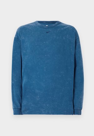 Dlhý rukáv modrý sveter z poškodeného bavlneného materiálu s okrúhlym výstrihom a malým čiernym logom Nike na hrudi. Jemná textura po celom povrchu.