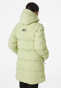 Giacca a vento verde chiaro con cappuccio, decorata con cuciture orizzontali e un logo sul retro. Tessuto morbido e imbottito, lunghezza fino a metà coscia.