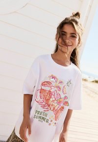 Fehér, oversized póló, színes rák és virág minta flitterekkel, "FRESH SUMMER DAYS" felirattal és lazább rövid ujjakkal.
