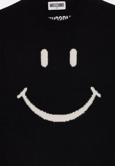 Pulover negru Moschino Kid cu un mare design alb zâmbitor pe partea frontală și etichetă vizibilă a brandului în interiorul gulerului.