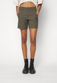 Olivgrüne Shorts aus Baumwollmischung, mit einem vorderen Knopfverschluss, seitlichen Taschen und dem The North Face-Logo am linken Bein.