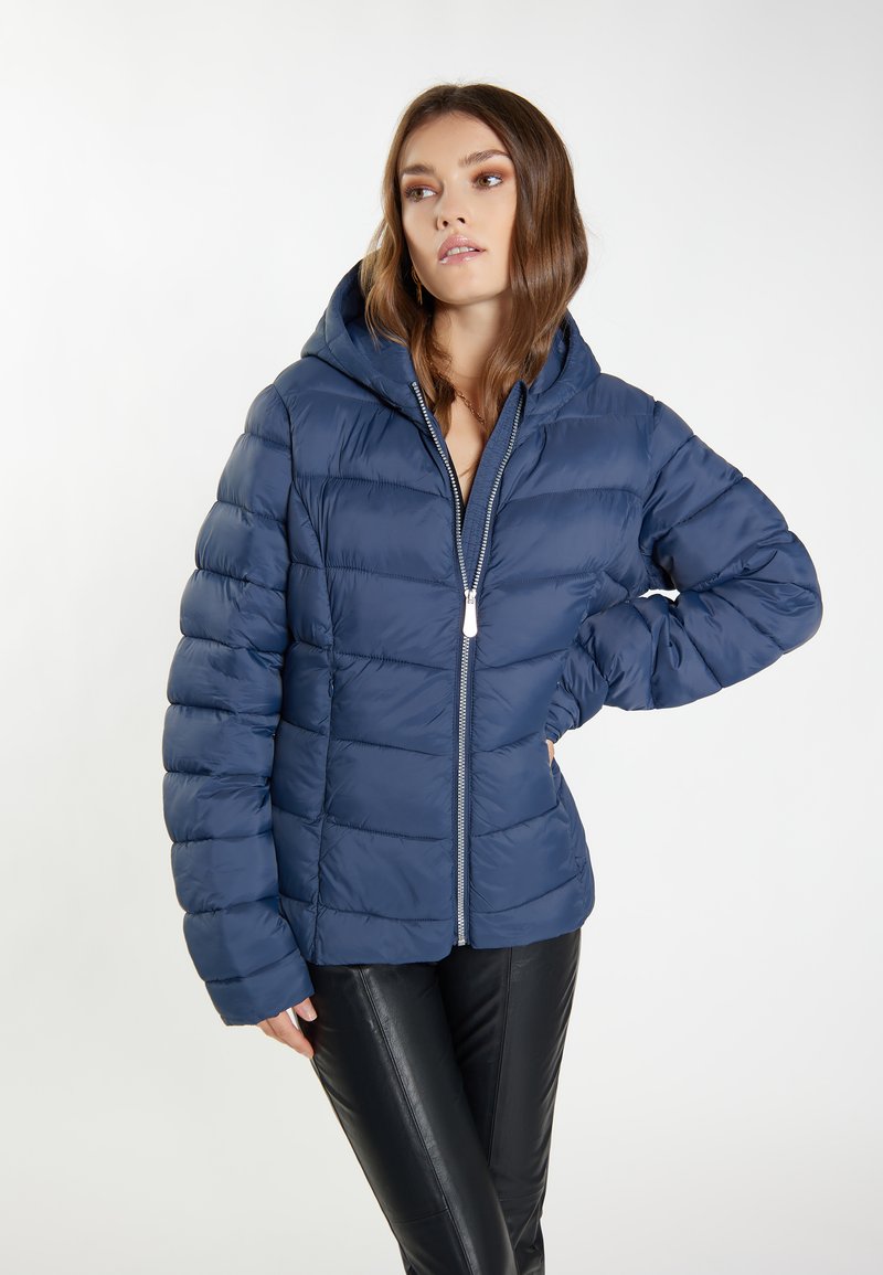 Giacca imbottita blu navy con chiusura a zip e cappuccio, caratterizzata da un'imbottitura trapuntata e una superficie testurizzata. Design leggero adatto per le giornate più fredde.