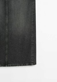 Partie basse d'une jupe en jean noire avec des coutures verticales visibles et un ourlet droit sur fond blanc.