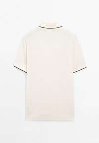 Polo a maniche corte in cotone bianco sporco con colletto e bordi delle maniche in contrasto scuro. Presenta un orlo spaccato e una texture liscia.