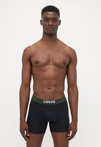 Črne bokserice z zelenim pasom, ki vsebujejo bel logo "Levi's". Material se zdi gladek in elastičen, prFit dizajn.