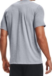 Šedé sportovní tričko s krátkými rukávy a kulatým výstřihem, s hladkou texturou a malým logem na zádech. Jednoduchý, klasický design.
