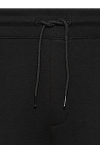 Svarte joggebukser med ribbet liv, med snor i livet og glatt tekstur. Inkluderer detalj med sidelomme.