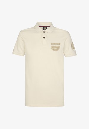 Kremowa koszulka polo wykonana z bawełny. Posiada kołnierzyk, trzy guziki oraz dwie ozdobne naszywki na piersi i rękawie.