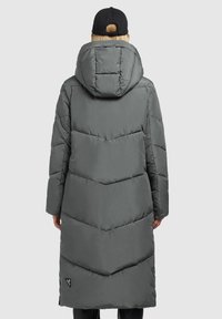 Lange grijze pufferjack met een chevronpatroon, een capuchon en een logopatch aan de onderlinkerkant. Glad materiaal en een ontspannen pasvorm.