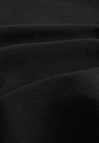 Schwarzer Stoff mit einer glatten Textur, der Falten und Knicke zeigt. Das Material wirkt weich und leicht dehnbar, mit gleichmäßiger Farbe.