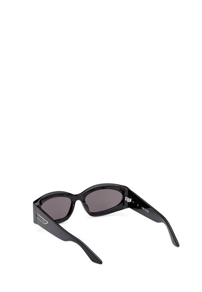 Czarne okulary przeciwsłoneczne z kanciastymi, oversized ramkami, ciemnymi soczewkami i błyszczącym plastikowym wykończeniem. Posiadają subtelny metalowy akcent z boku.