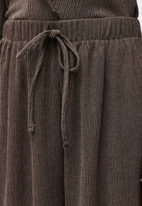 Καφέ παντελόνι από υφή υφάσματος με ελαστική μέση και δεμένο κορδόνι στο μπροστινό μέρος.